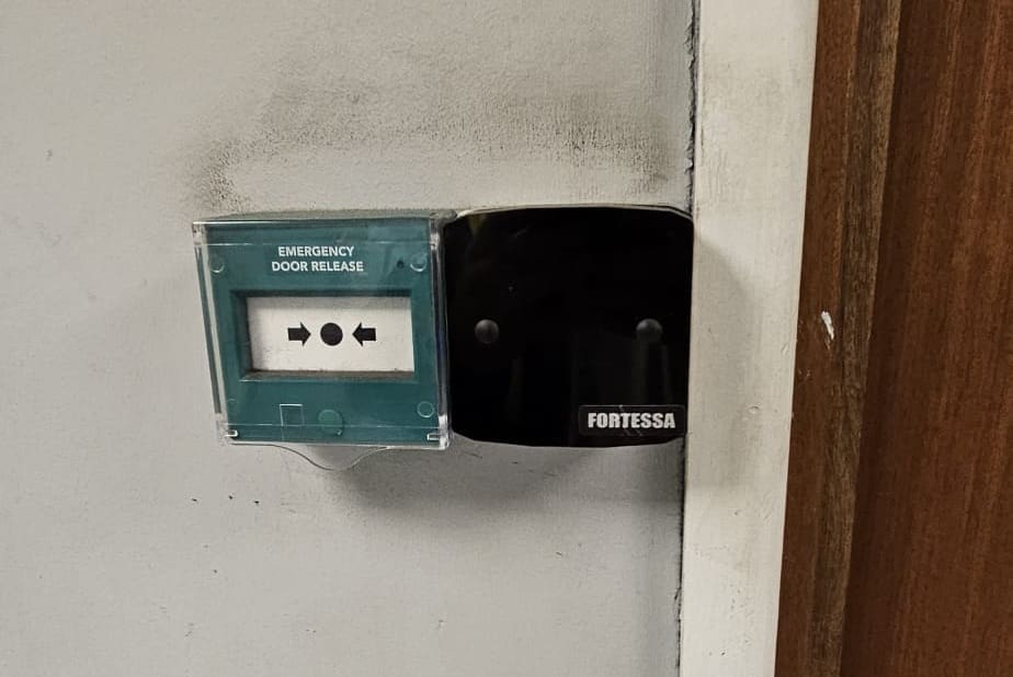 Emergency door release beside an electronic access control reader